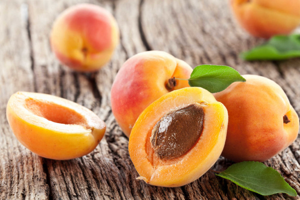 Apricot cut open with whole apricots behind.