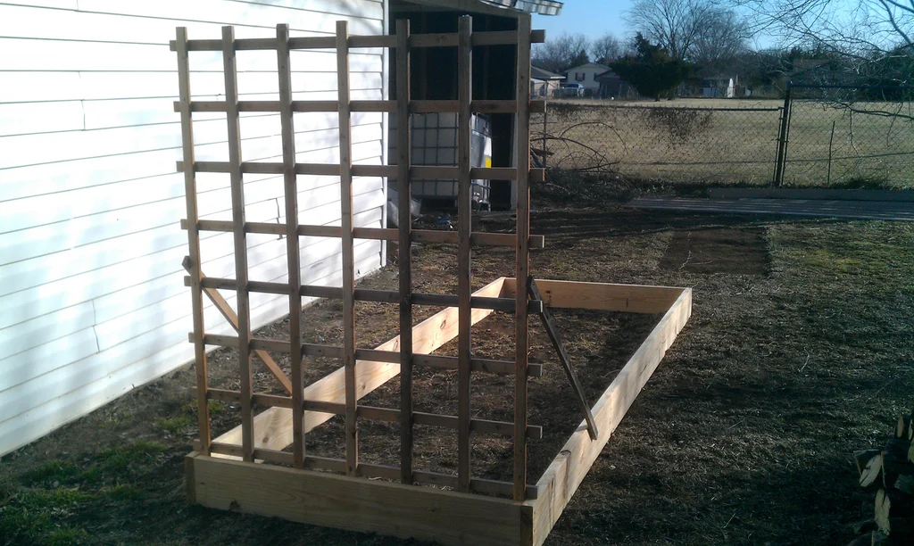 Empty raised bed with trellis on front of it.